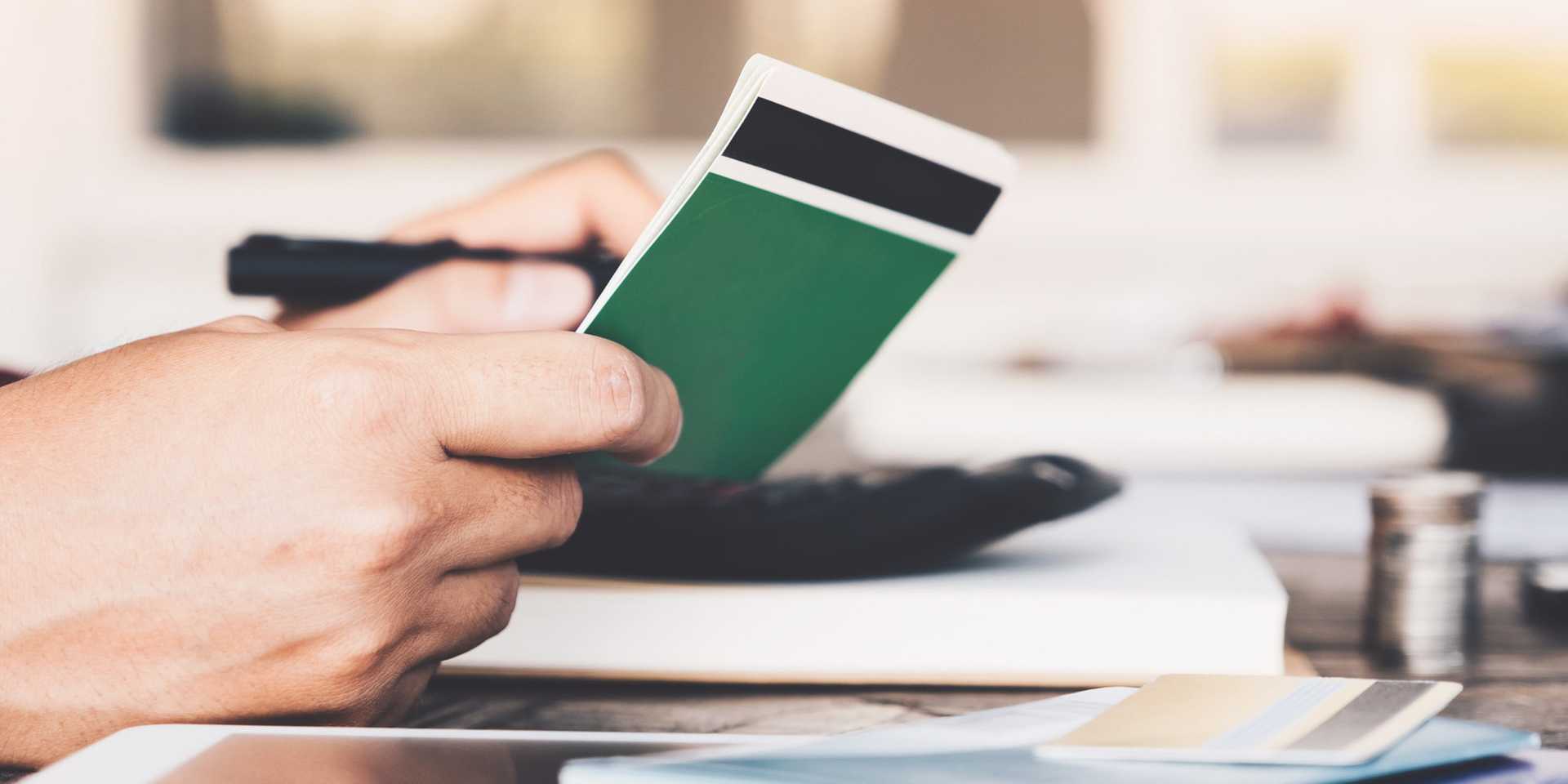 An accountant's hands holding a green balance book