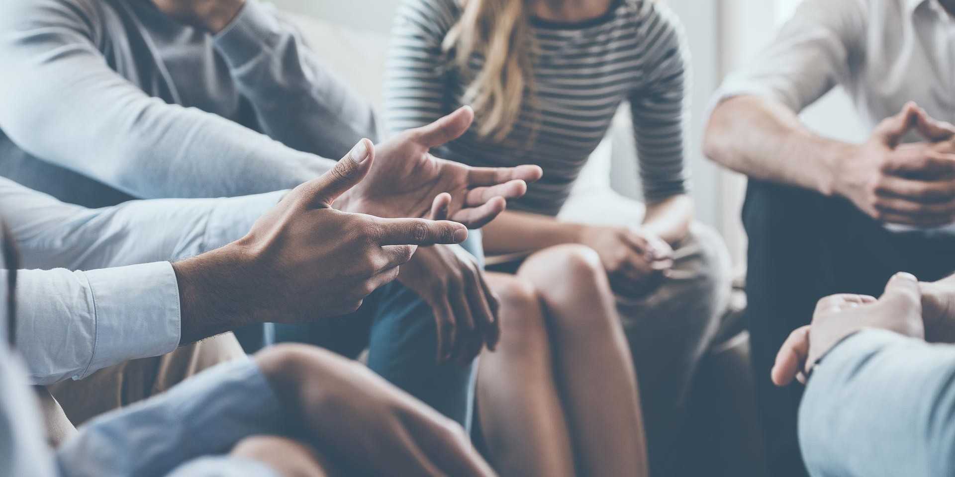 A group of people sitting in a circle having a discussion, with one person's hands outstretched