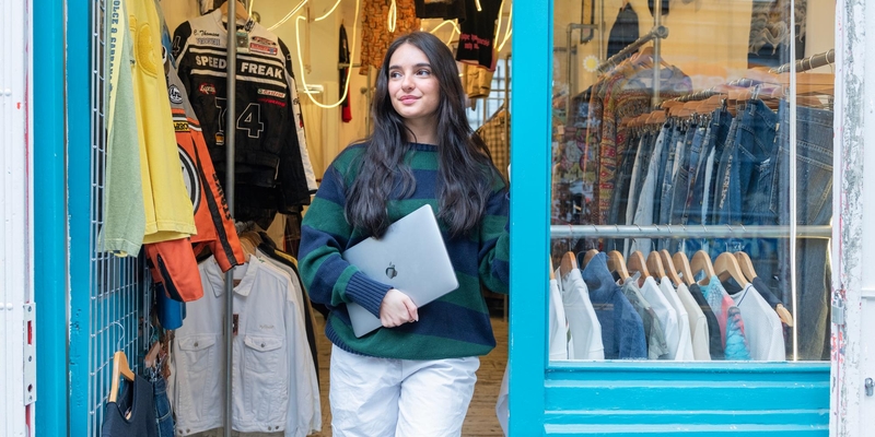 Grace Hardy holds a laptop outside an independent clothes shop